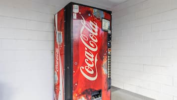 A Coca-Cola vending machine in a hallway with white brick walls.