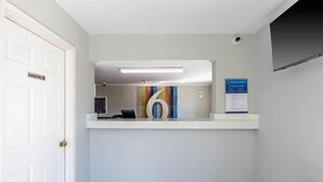 Et receptionsområde med et hvidt receptionsskrivebord, et ur og et skilt, der byder gæster velkommen.