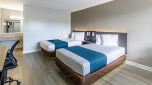 Et hotelværelse med to senge, et skrivebord og en stol.