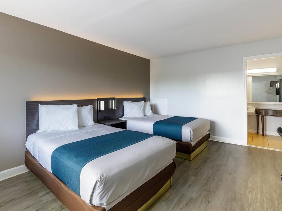 A hotel room with two beds, a desk, and a chair.