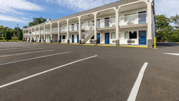 Un motel con una escalera central, varios balcones y un estacionamiento.
