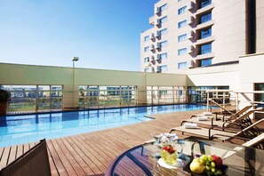 Una piscina al aire libre, sillones reclinables de piscina