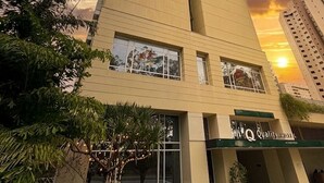 A tall, beige building with a modern design, featuring a large glass entrance and signage for 'Q Quality Inn.'