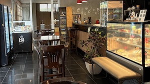 A restaurant interior with tables, chairs, a counter, and a display case.