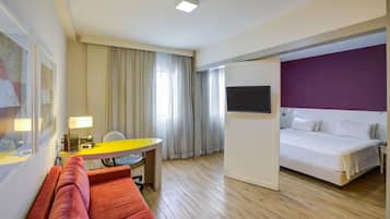 A hotel room with a bed, a desk with a chair, a small table, and a couch.