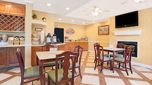 A spacious kitchen with a dining area, wooden cabinets, a wine rack, and a fireplace. - Baymont by Wyndham Pearl (Pearl)