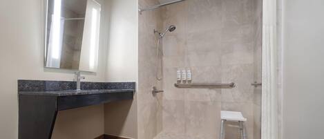 A modern bathroom with a shower, a vanity with a mirror, and a small stool.