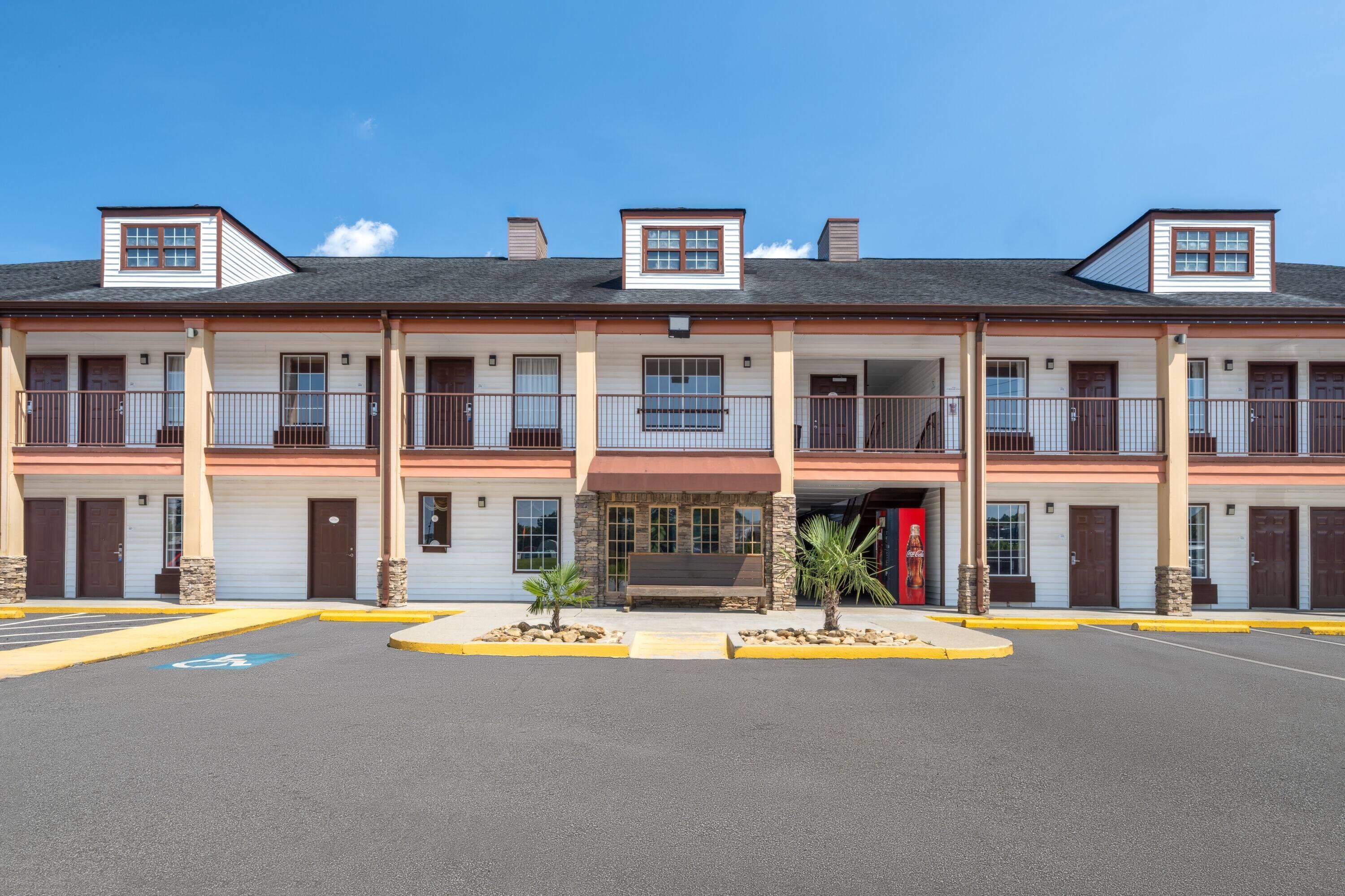 Un motel à plusieurs étages, doté d’une entrée principale, de balcons et d’un parking.