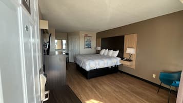 A hotel room with a bed, desk, chair, and a small table.