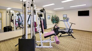 Une salle de sport équipée de machines de cardio, d’un tapis de course et d’un miroir.