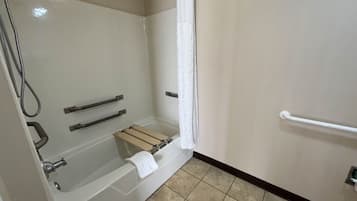 Een badkamer met douche, handgrepen, een handdoekrek en toilet.