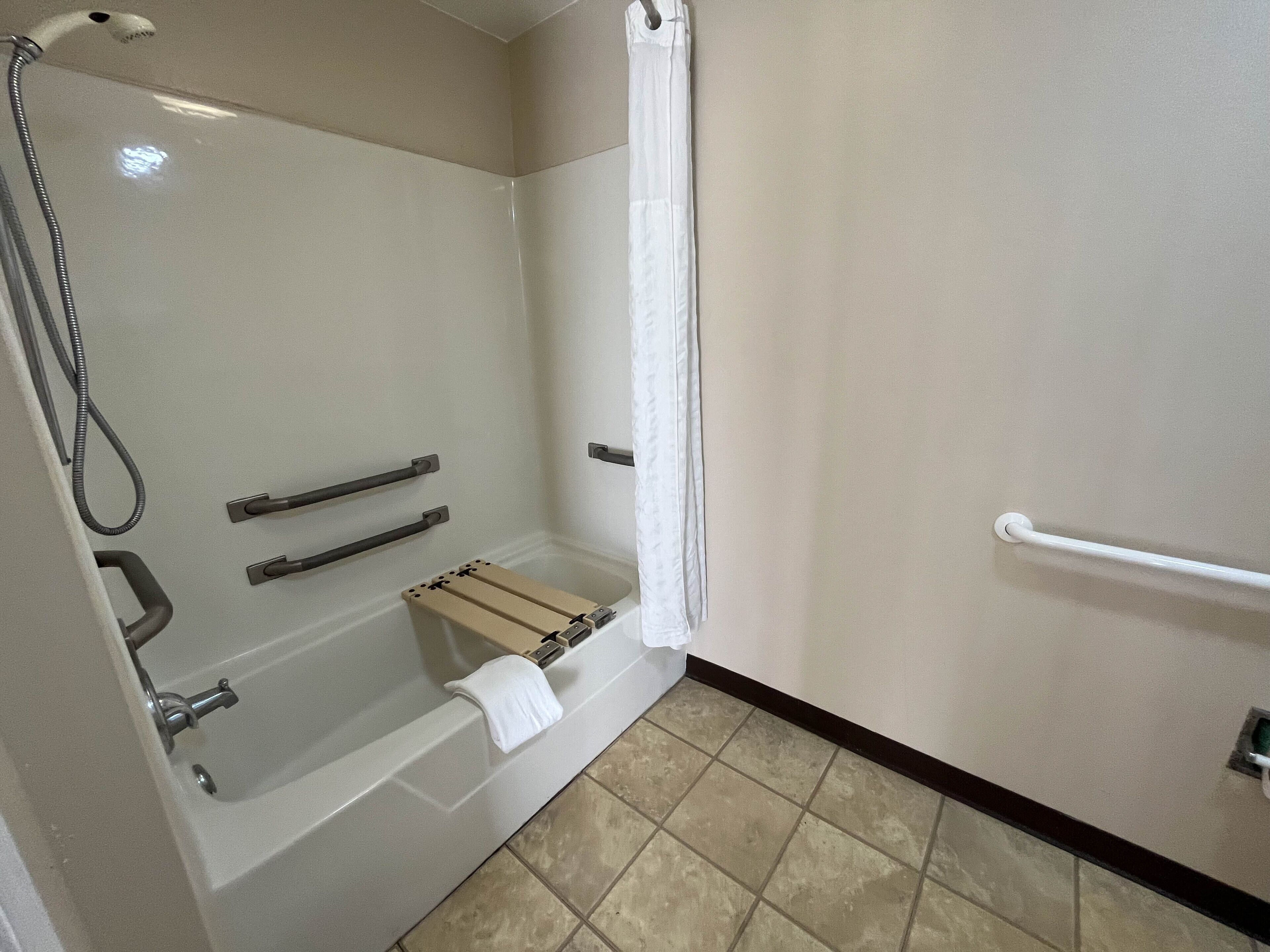 Une salle de bain équipée d’une douche, de barres d’appui et d’un porte-serviettes.