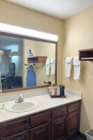 A bathroom with a large mirror, a sink, a towel rack, and a coffee maker.