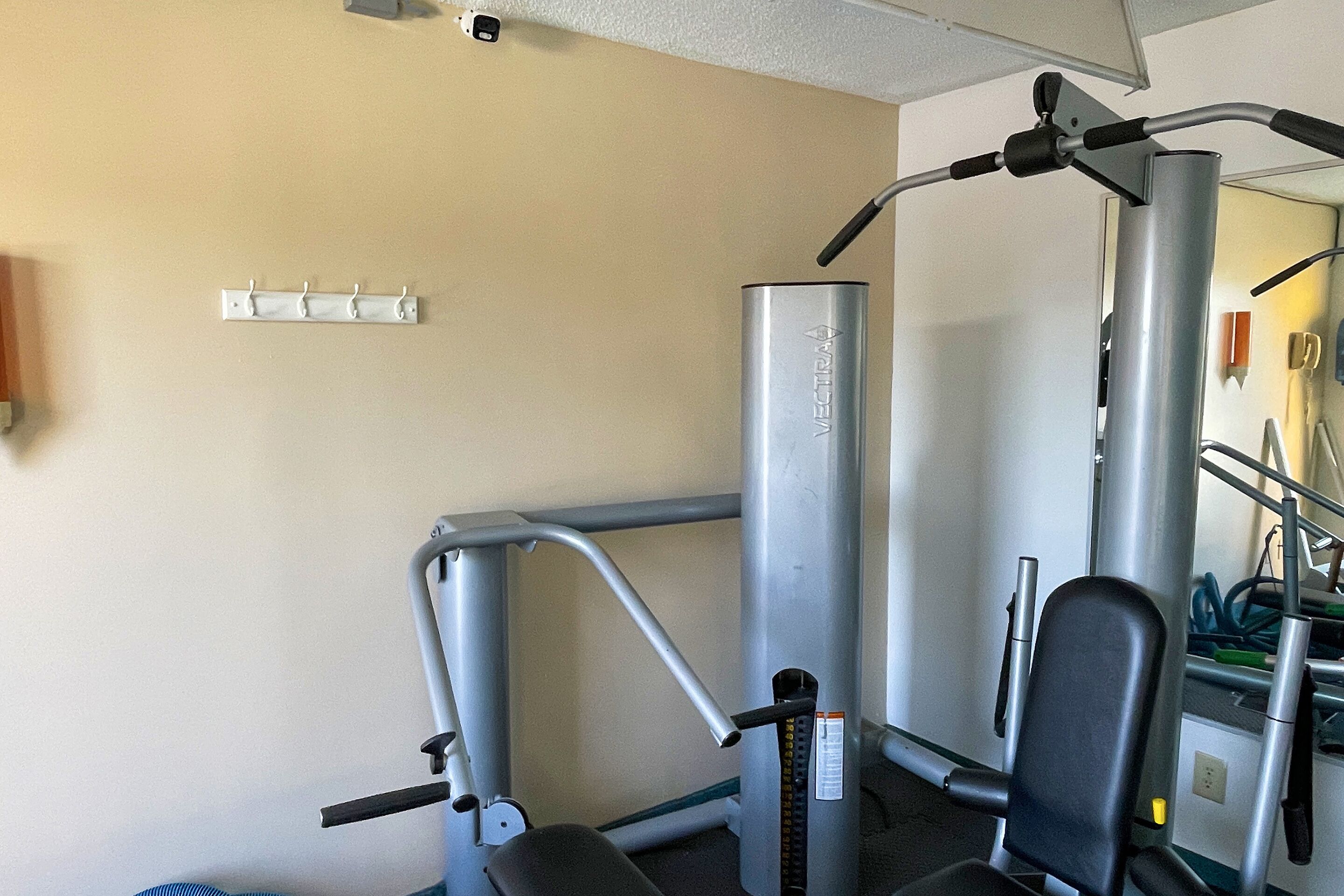 A gym with exercise equipment, a wall-mounted mirror, and a towel rack.