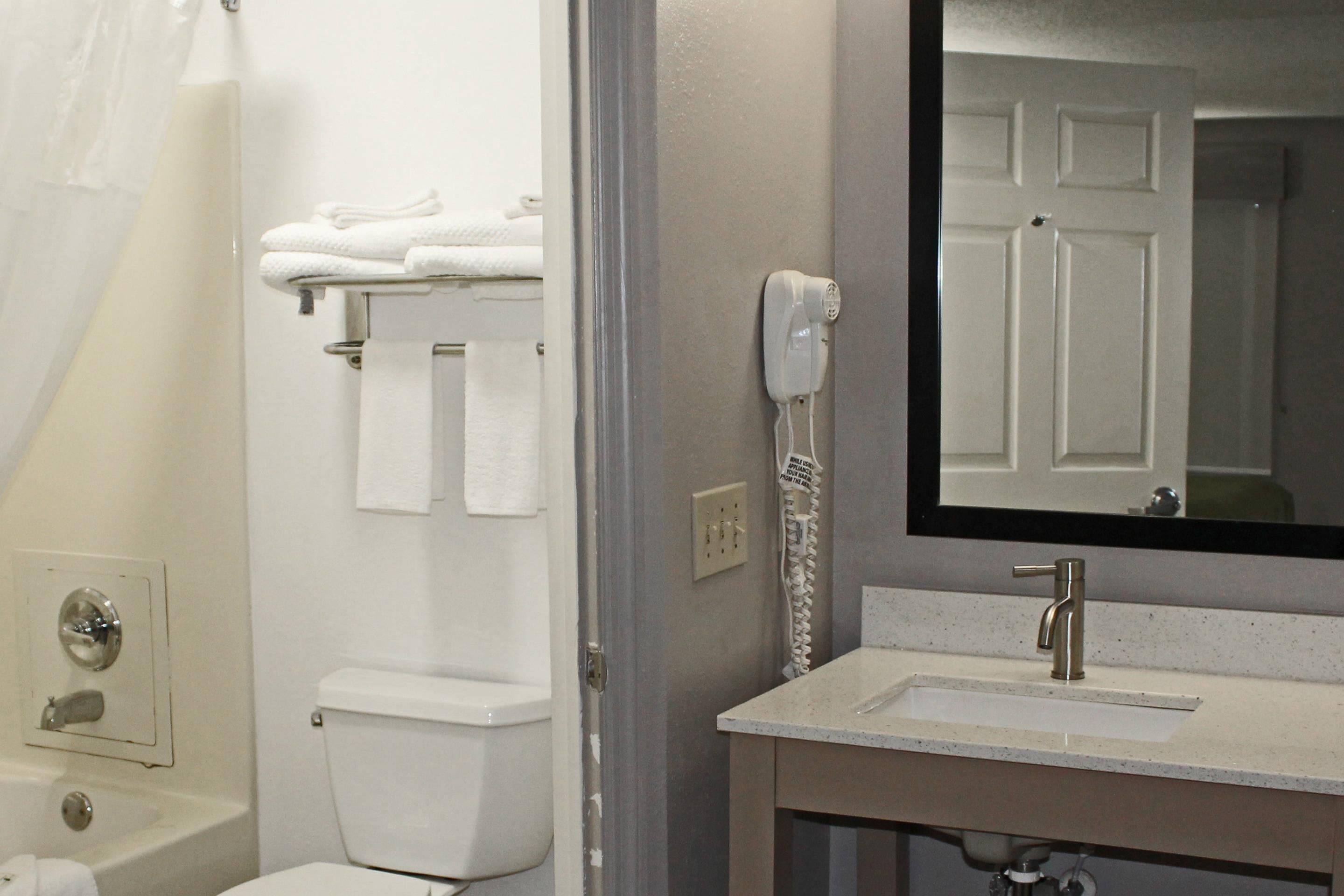 A bathroom with a toilet, a sink, a mirror, and a towel rack.