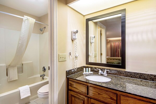 A bathroom with a bathtub, toilet, and a sink with a mirror above it.