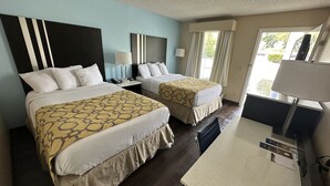 A hotel room with two beds, a desk, and a TV. - Baymont by Wyndham Thomasville (Thomasville)