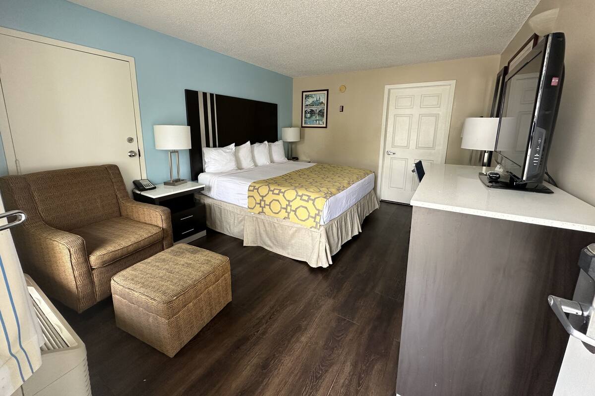 Una habitación de hotel con cama, escritorio, silla, televisor y puerta.