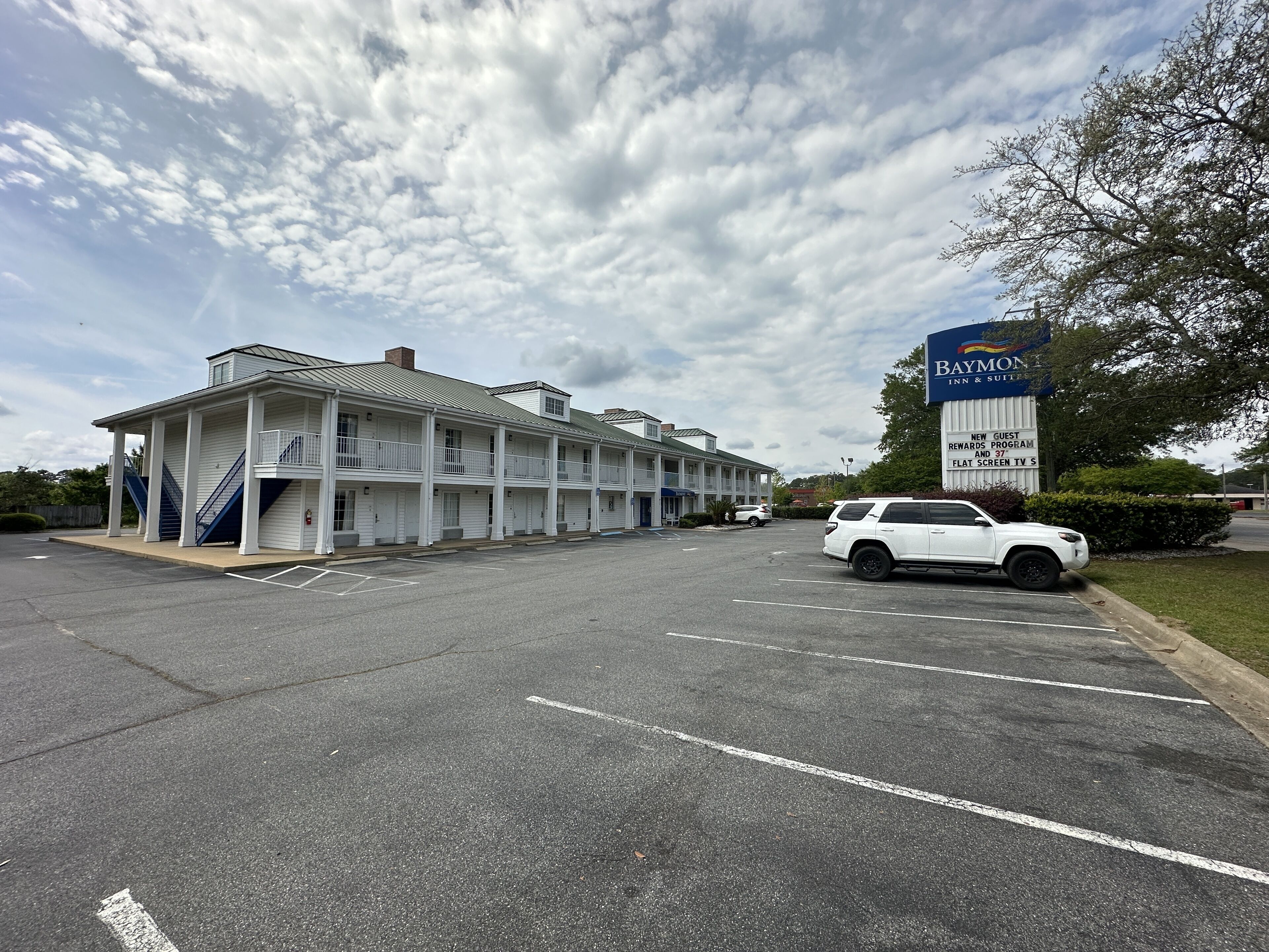 Un motel con una struttura a due piani, un cartello con schermo piatto e un parcheggio.