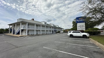 Un motel con una struttura a due piani, un cartello con schermo piatto e un parcheggio.