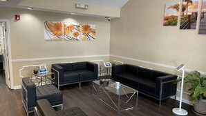 A modern lobby with a black leather sofa, a glass coffee table, and a potted plant. - Baymont by Wyndham Thomasville (Thomasville)