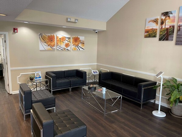 A modern lobby with a black leather sofa, a glass coffee table, and a potted plant.
