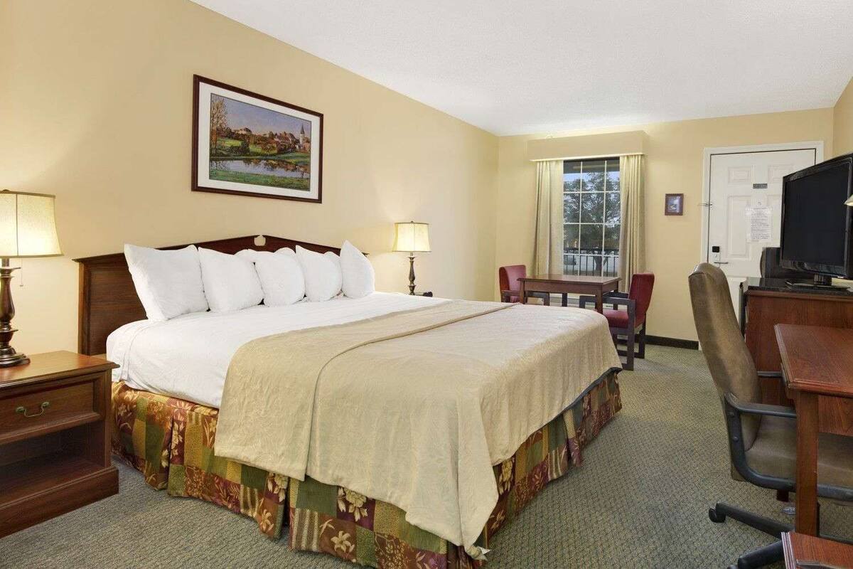 Habitación de hotel con una cama grande, dos lámparas de noche, un escritorio con silla, televisión y una ventana con cortinas.