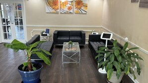 A reception area with a black leather sofa, a glass coffee table, and potted plants. - Baymont by Wyndham Thomasville (Thomasville)