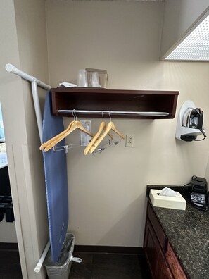 Guest room with a functional layout, featuring a shelf, metal rack, and countertop with a coffee maker.