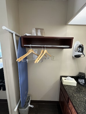 Guest room with a functional layout, featuring a shelf, metal rack, and countertop with a coffee maker.