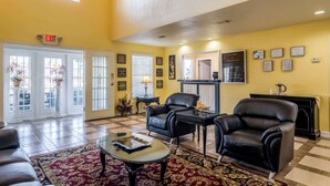 A spacious lobby with a high ceiling, a reception desk, black leather chairs, a coffee table, and a red patterned rug. - Quality Inn Washington GA (Washington)