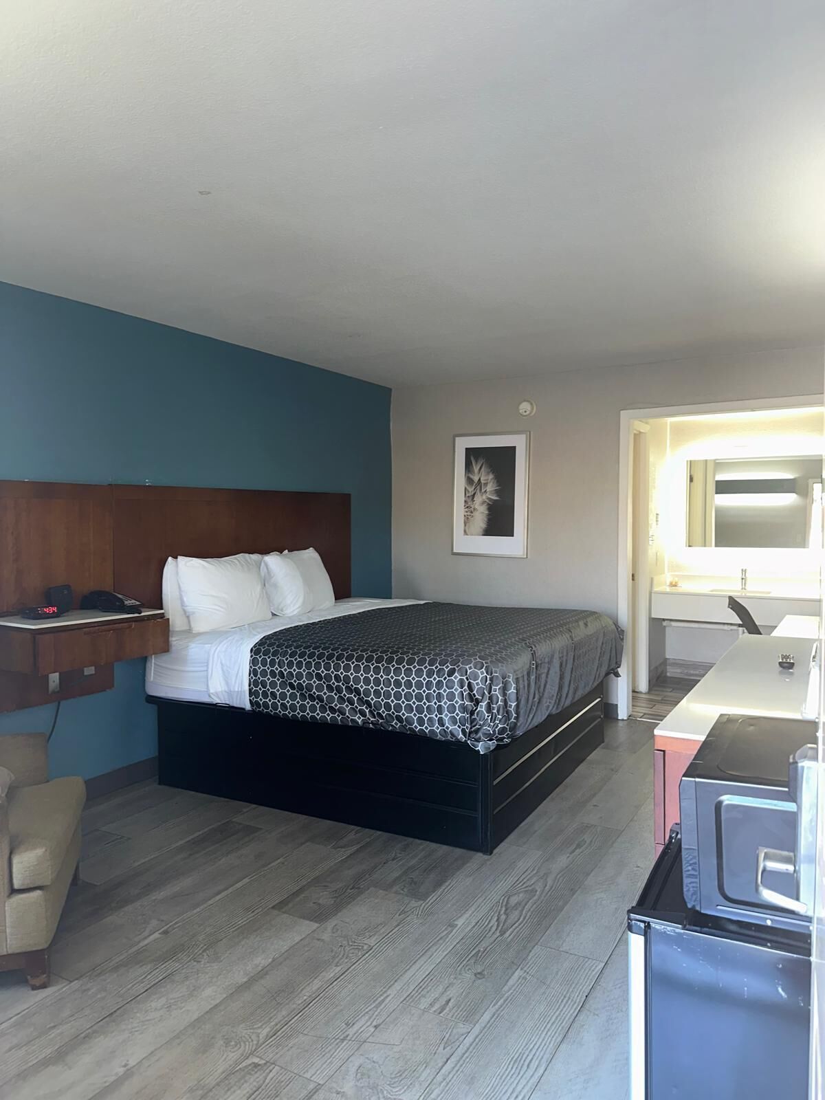 Quarto com cama, mesa de cabeceira e escrivaninha com cadeira.