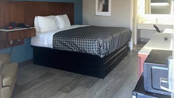 Quarto com cama, mesa de cabeceira e escrivaninha com cadeira.
