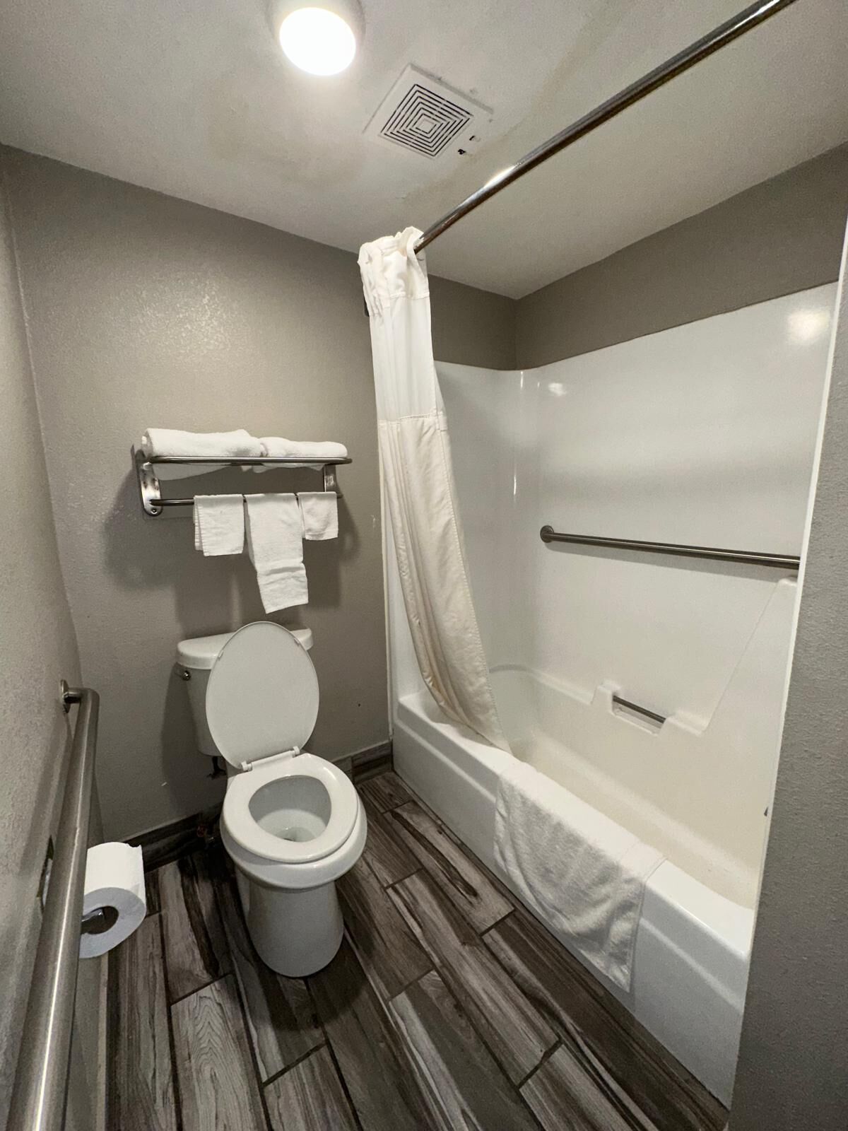 A modern bathroom with a toilet, a shower with a glass door, and a towel rack with folded towels.