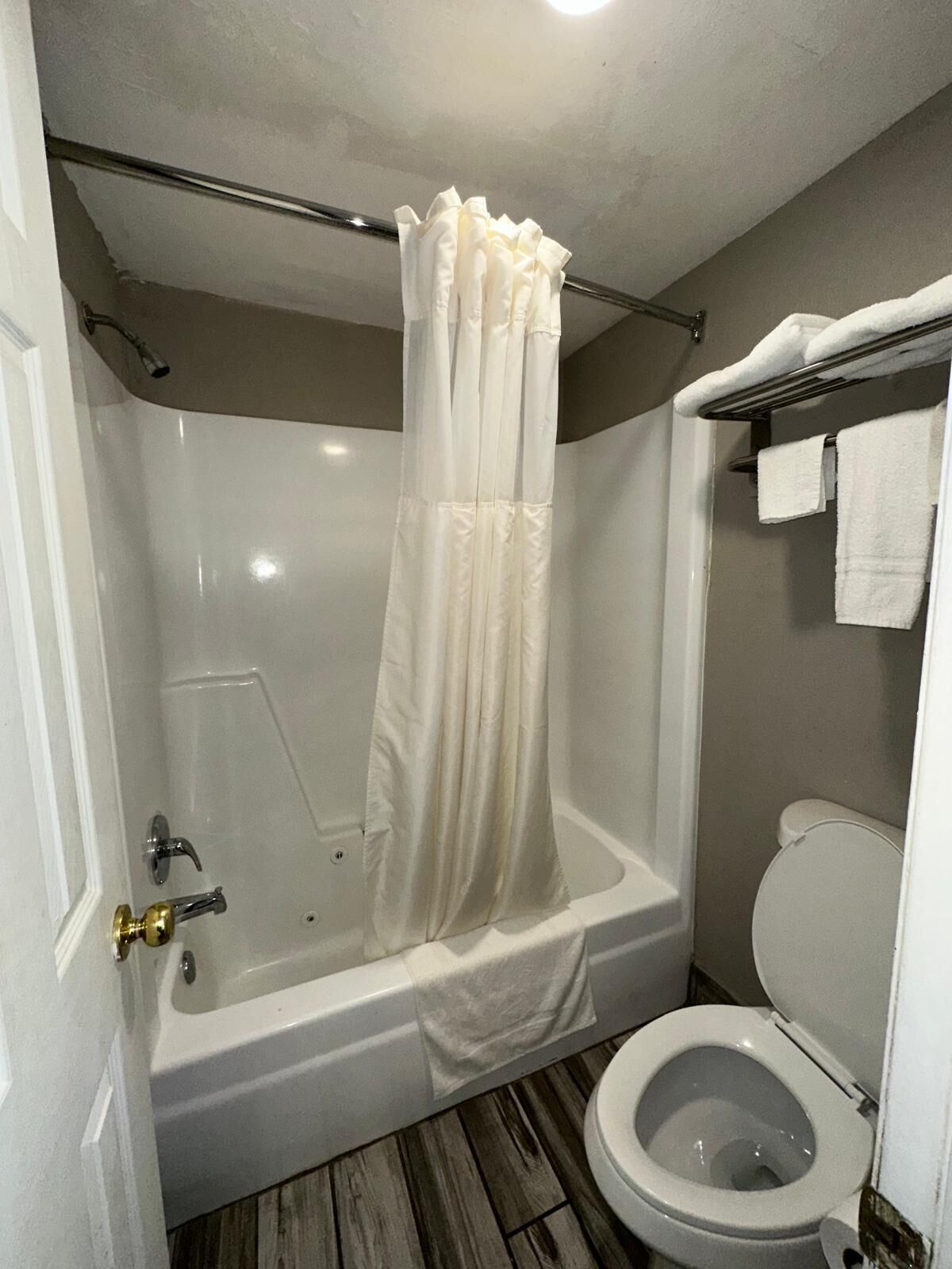 Un baño con bañera, cortina de ducha e inodoro.