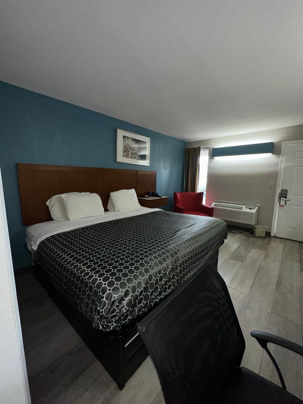 Una habitación de hotel con una cama grande, un escritorio, una silla y una puerta.