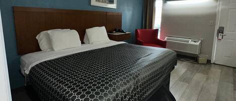 Una habitación de hotel con una cama grande, un escritorio, una silla y una puerta.
