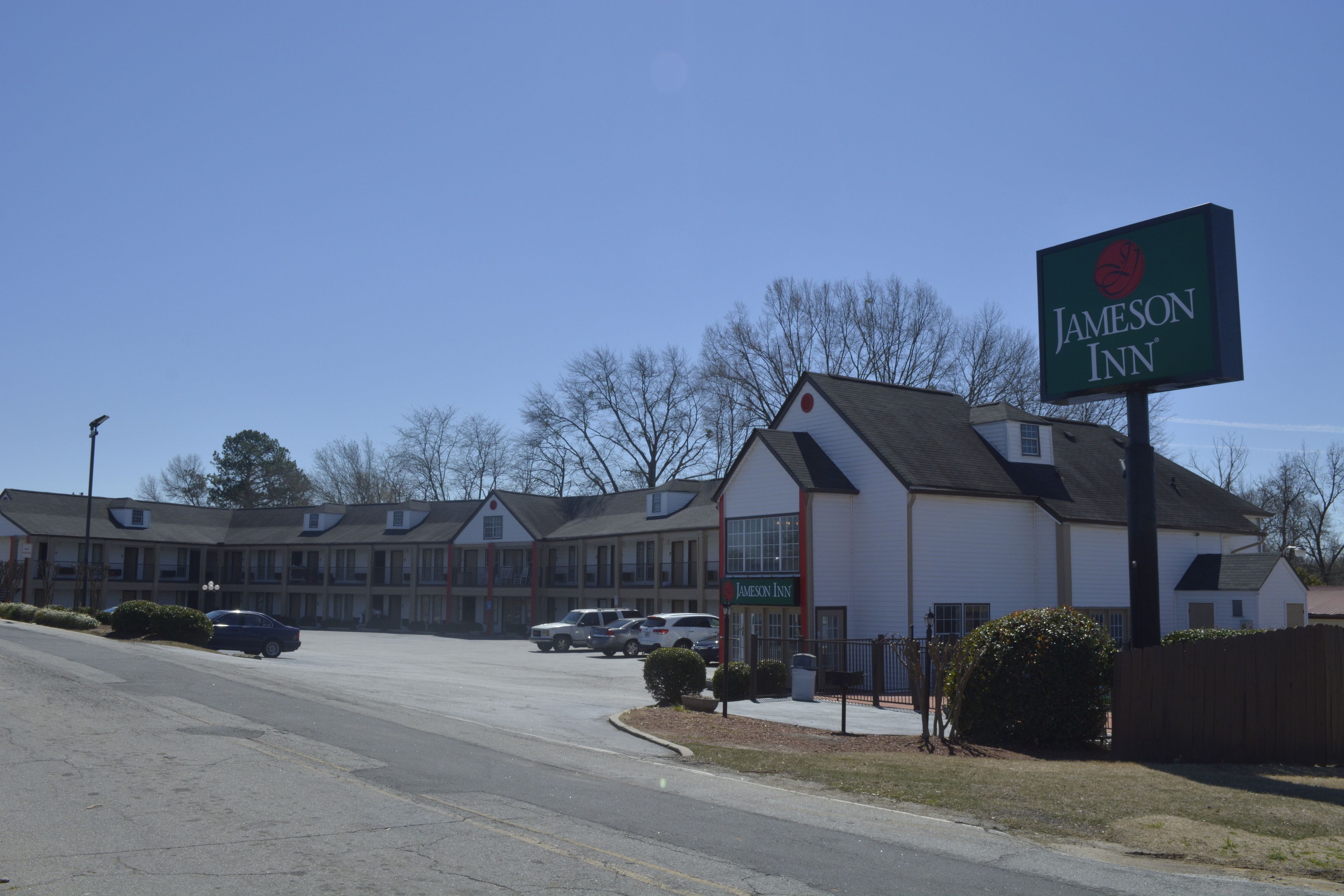 A Jameson Inn with a large sign, a parking lot, and several buildings in the background.
