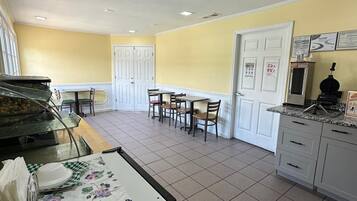 Comedor con barra libre, una mesa con sillas y zona de cocina con armarios y electrodomésticos.