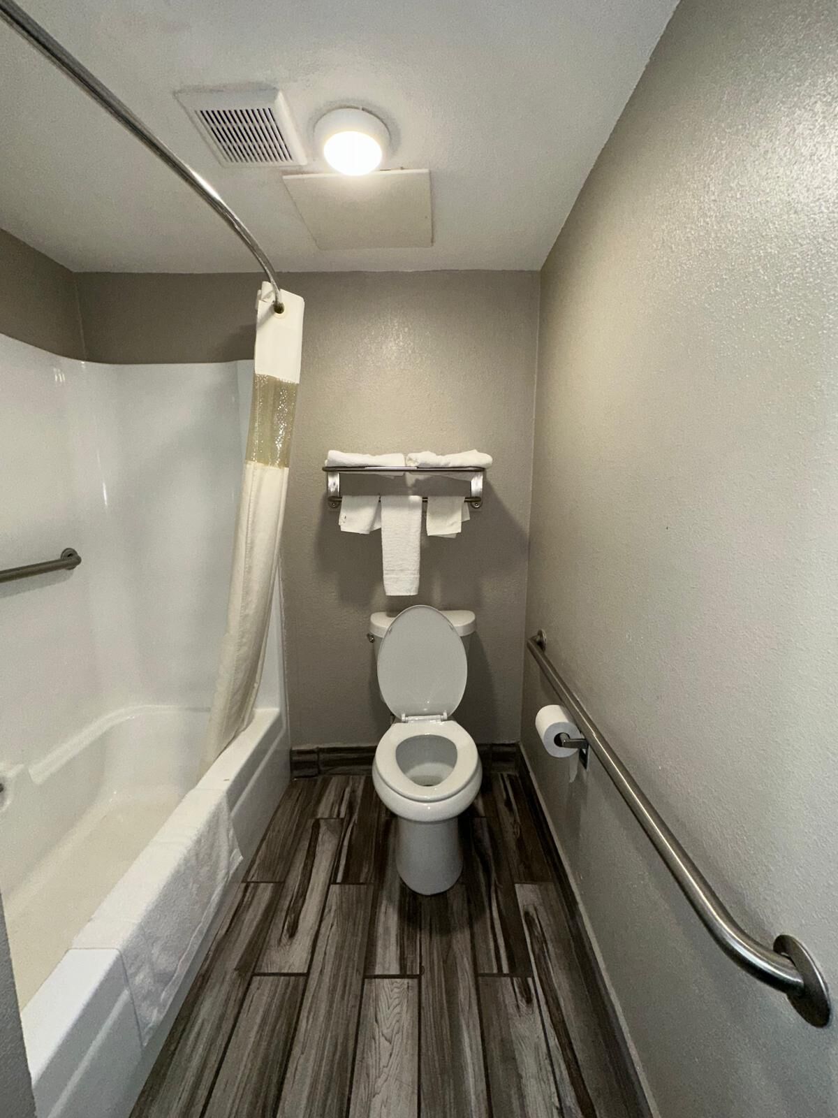 Un baño pequeño con ducha, inodoro y un perchero para toallas.