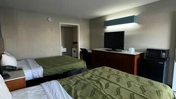 Et hotelværelse med to senge, et skrivebord med telefon, fjernsyn og en mikroovn.