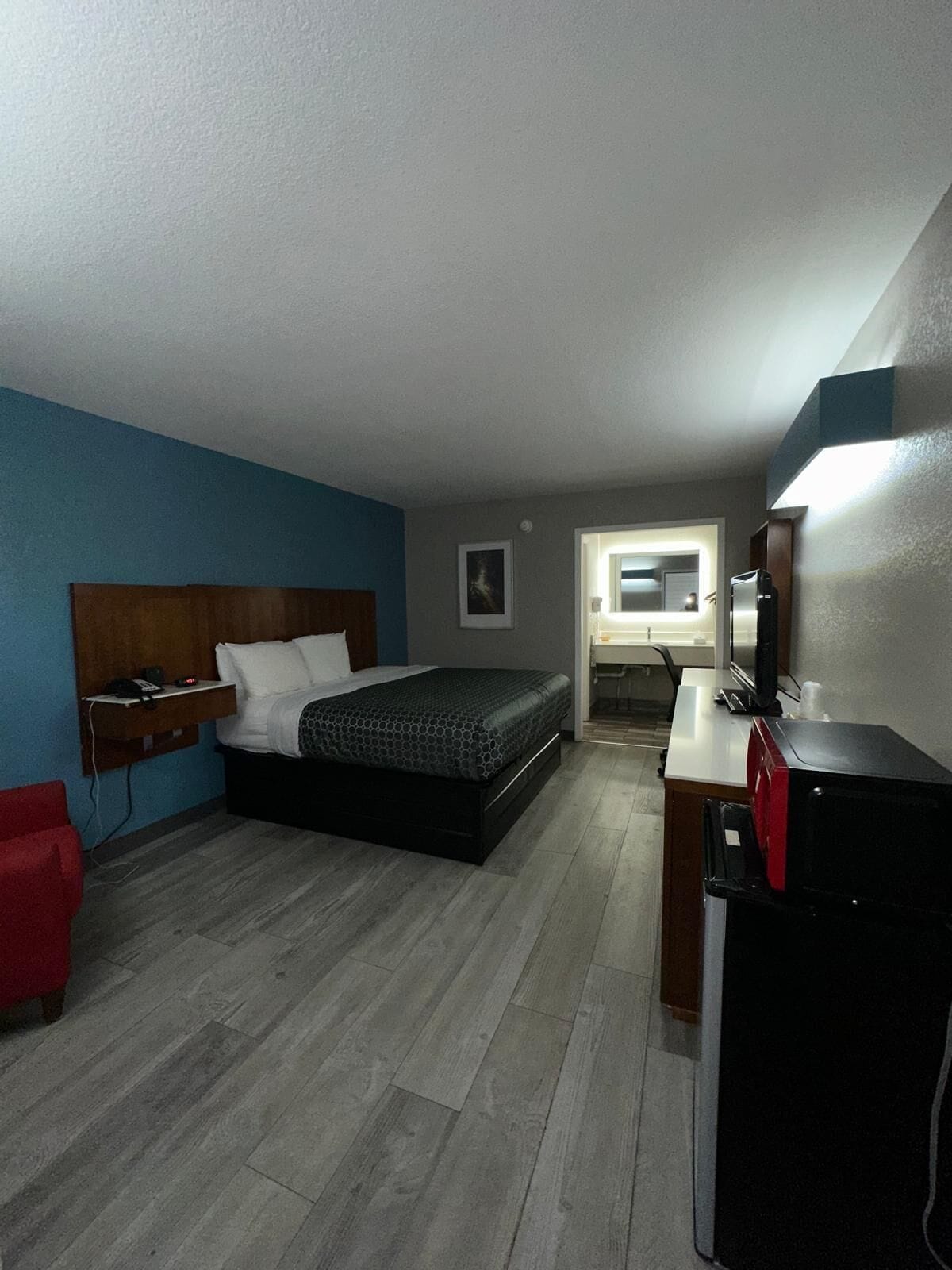 A bedroom with a bed, a desk, a chair, and a TV.