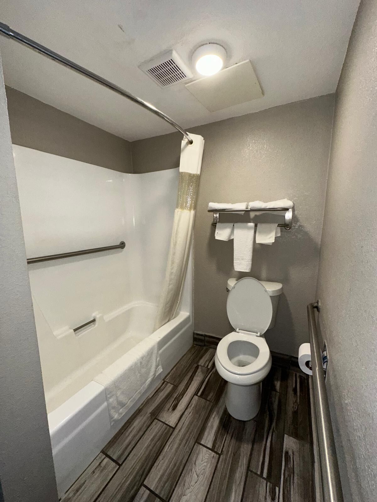 A small, modern bathroom with a shower, toilet, and a bathtub.