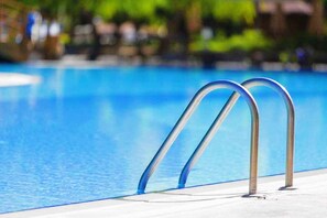 Una piscina al aire libre de temporada, sillones reclinables de piscina