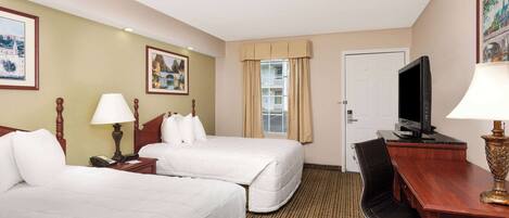 A hotel room with two beds, a desk, a television, and a chair.