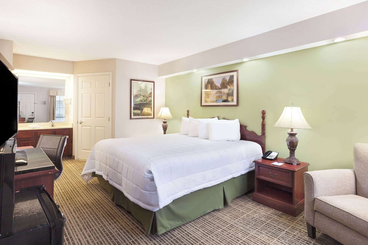 A hotel room with a bed, bedside tables, a desk, and a chair.