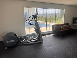Um quarto com bicicleta ergométrica, sofá e televisão.