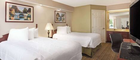 A hotel room with two beds, a desk, a chair, and a television.