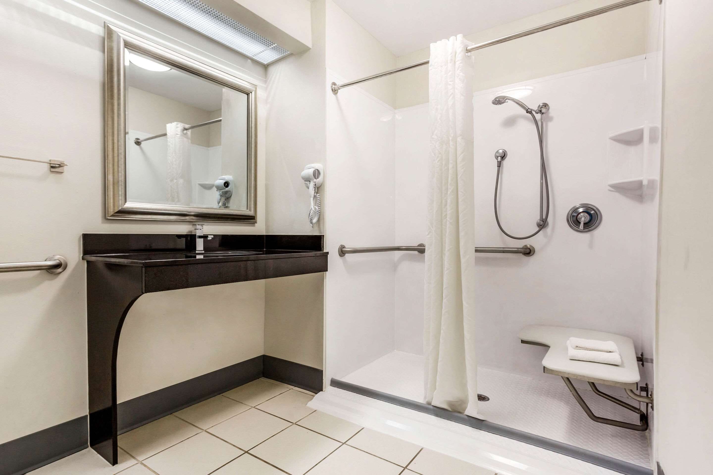 A bathroom with a shower, a sink, and a mirror.