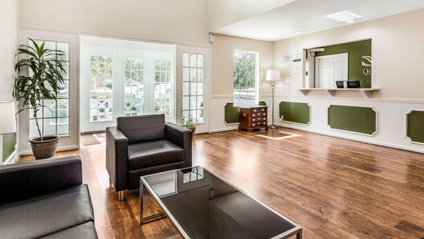 A spacious lobby with a wooden floor, a reception desk, a large mirror, and a potted plant. - Quality Inn Lancaster (Lancaster)
